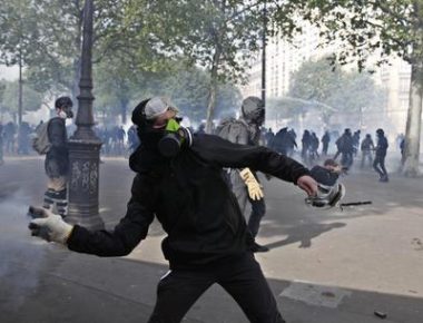 epa06704977 A masked youth protester throws stones in clashes with French police forces during a demonstration of workers from the private and public sectors as well as labor unions on the occasion of the annual May Day marches on the International Workers' Day, in Paris, France, 01 May 2018. French unions led a movement of strikes to protest against government reforms in the public services.  EPA/YOAN VALAT