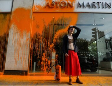 A member of the environmental activist group Just Stop Oil reacts after spraying orange paint on the window shop of the Aston Martin car show room, in central London, on October 16, 2022 as part of a series of actions. - Just Stop Oil, which wants an end to new fossil fuel licensing and production, are involved in a month-long series of protests in central London. (Photo by ISABEL INFANTES / AFP)