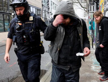 Police officer David Baer pulls a man, who was caught smoking fentanyl, to issue him a citation and to offer him a card that lists a 24-hour treatment hotline which he can call to get his citation dismissed in Portland, Oregon, U.S. February 7, 2024.  REUTERS/Deborah Bloom